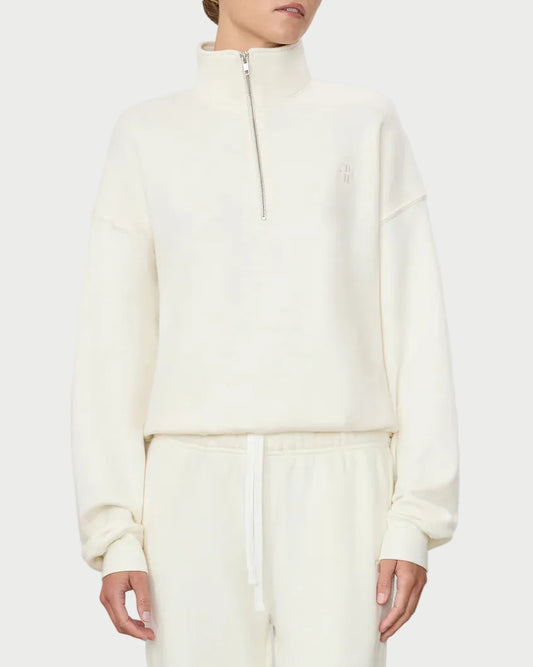 Woman wearing a white zip-up hoodie and pants on a light gray background