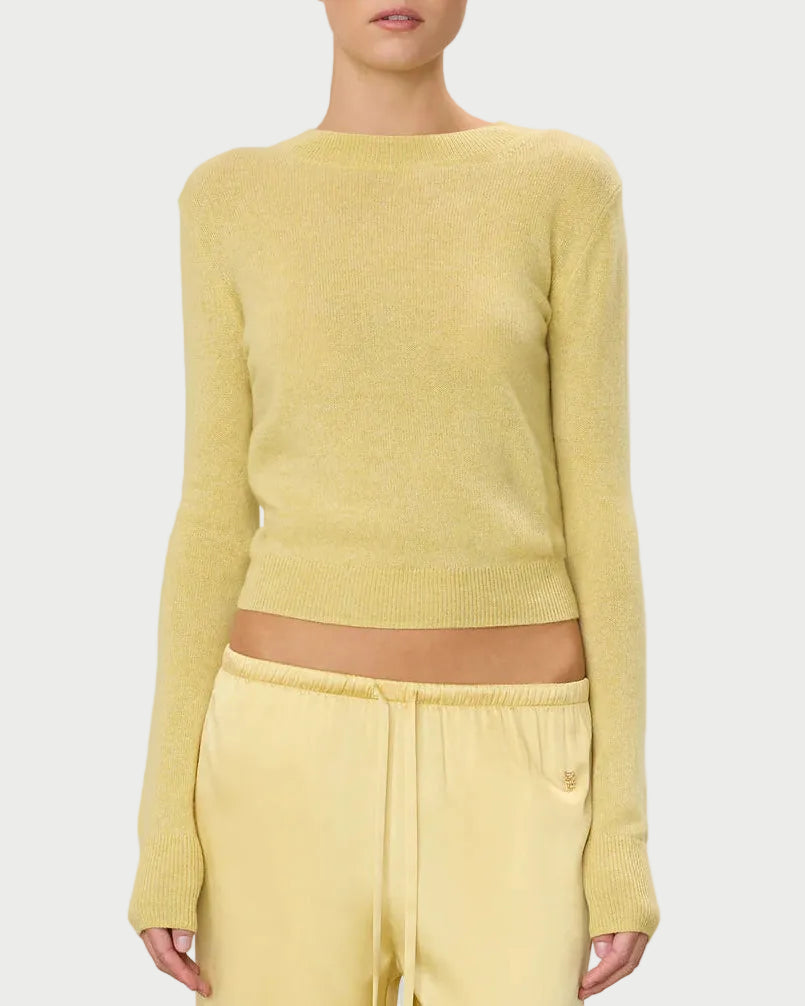 Woman wearing a yellow sweater and pants on a light gray background