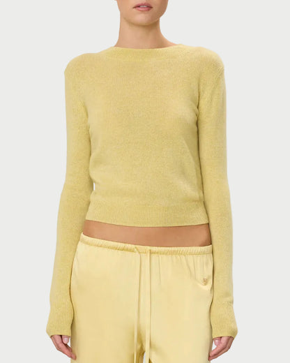 Woman wearing a yellow sweater and pants on a light gray background