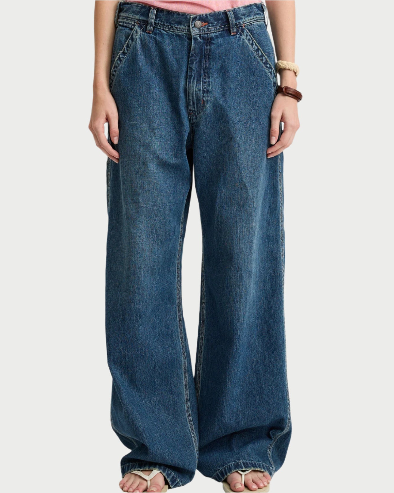 A person stands barefoot against a plain background, hands in pockets, wearing Denimist's The Teri Wide Leg Carpenter Pant. The relaxed, wide-leg 100% cotton fit and ankle bunching offer effortless, laid-back style.