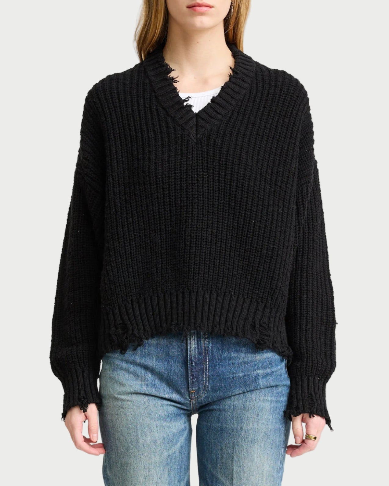 Person wearing a black sweater and blue jeans on a white background