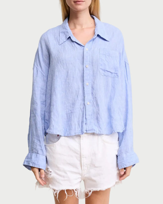 Woman wearing a light blue button-up shirt and white shorts on a beige background