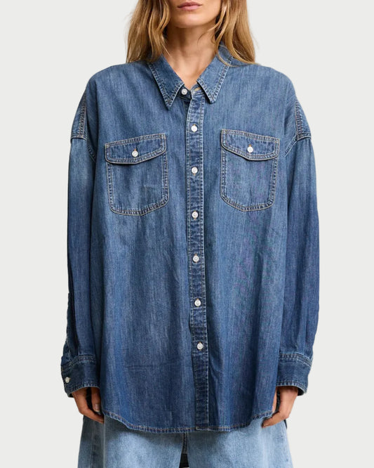 Woman wearing a blue denim shirt against a plain background