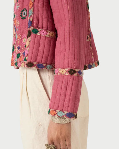 Close-up of a pink embroidered traditional outfit with white pants on a plain background