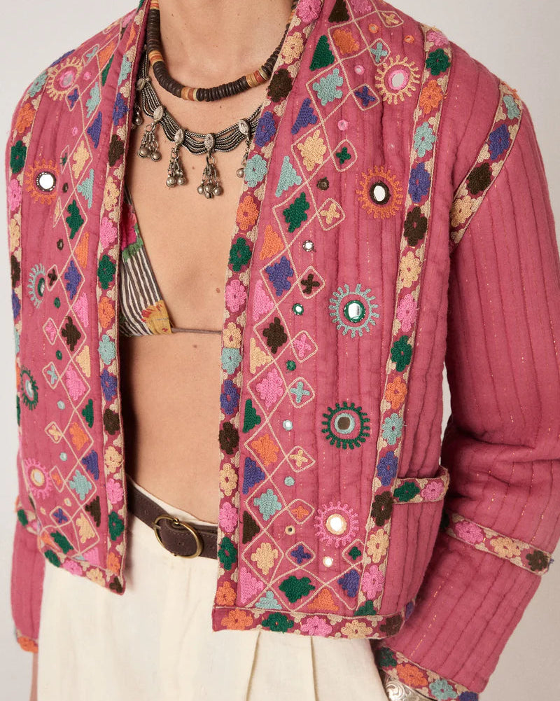 Person wearing a colorful embroidered jacket with a neutral background