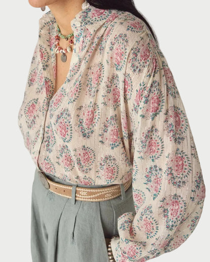 Woman wearing a floral blouse with a neutral background