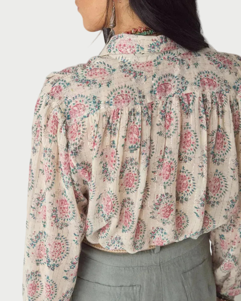Person wearing a floral blouse with a neutral background