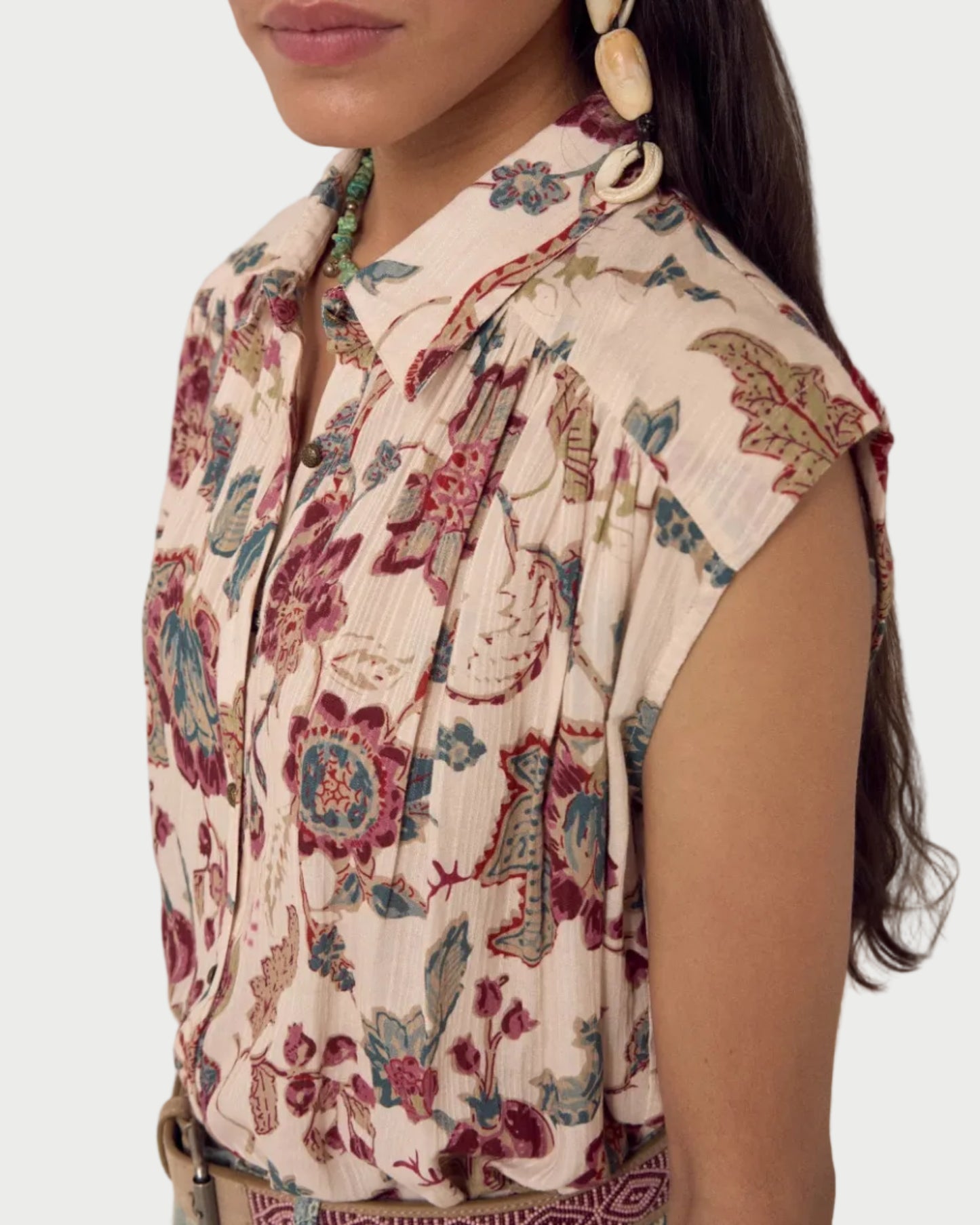 Woman wearing a sleeveless floral blouse with a neutral background
