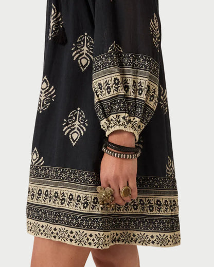 Black dress with white pattern worn by a person on a plain background