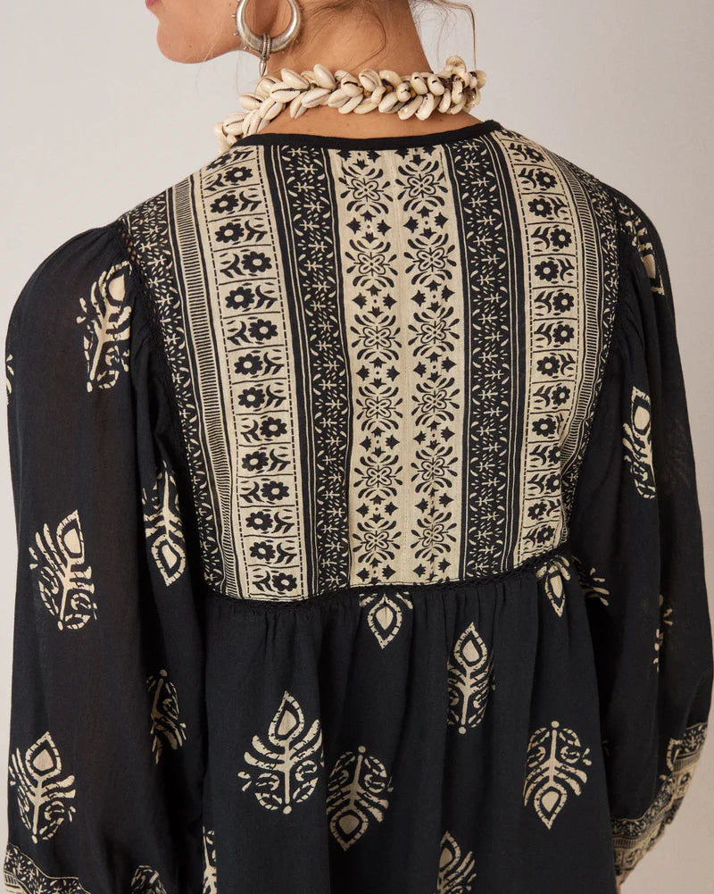Black and white patterned blouse with long sleeves on a neutral background