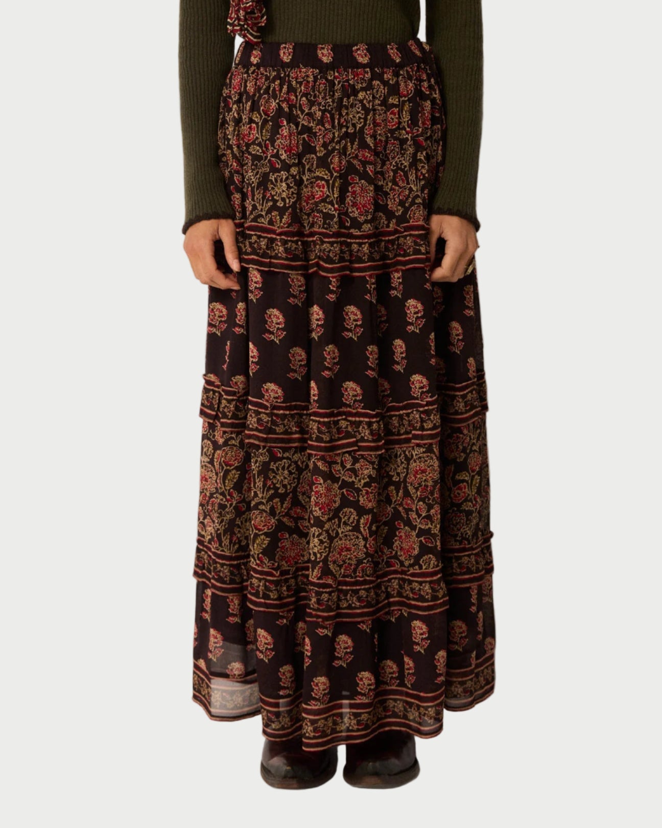 Person wearing a long patterned skirt with a plain background