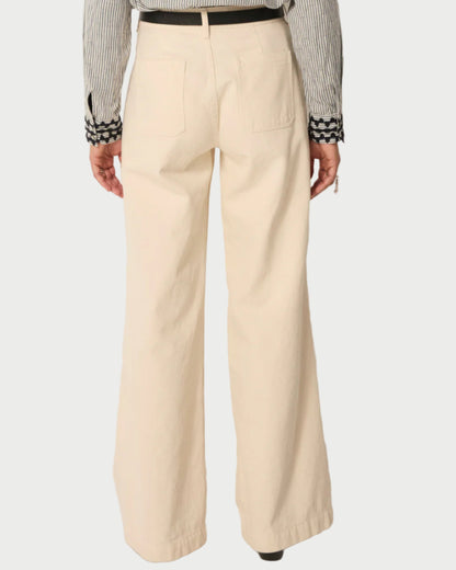 A person shown from the back wears Maison Hotel Hamlet Pants—high-waisted, recycled cotton, wide-leg with two back pockets—paired with a striped long-sleeve shirt featuring patterned cuffs.