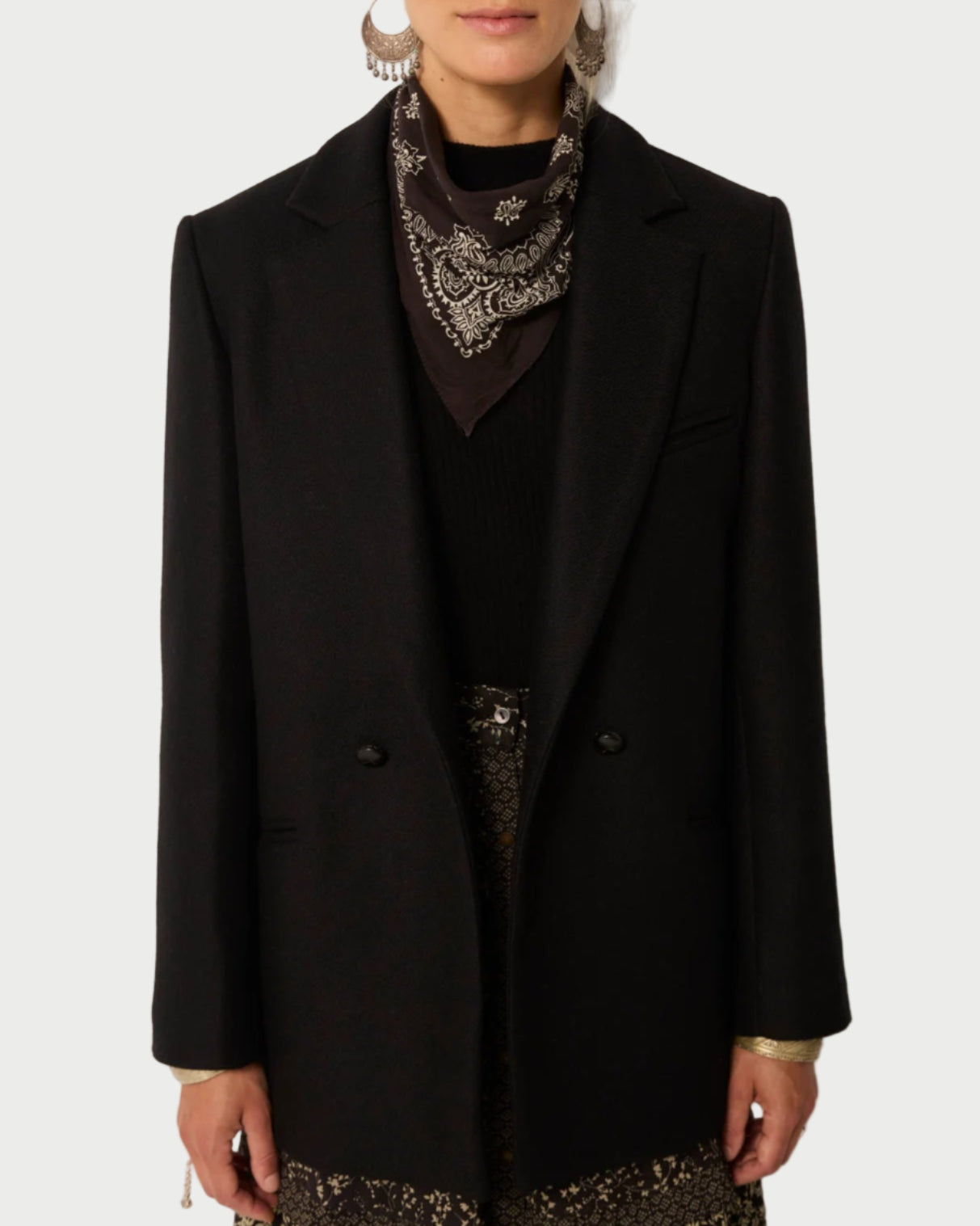 Person wearing a black coat with a patterned scarf against a plain background