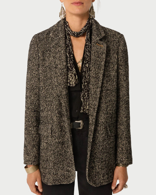 Person wearing a patterned blazer over a black top with a plain background