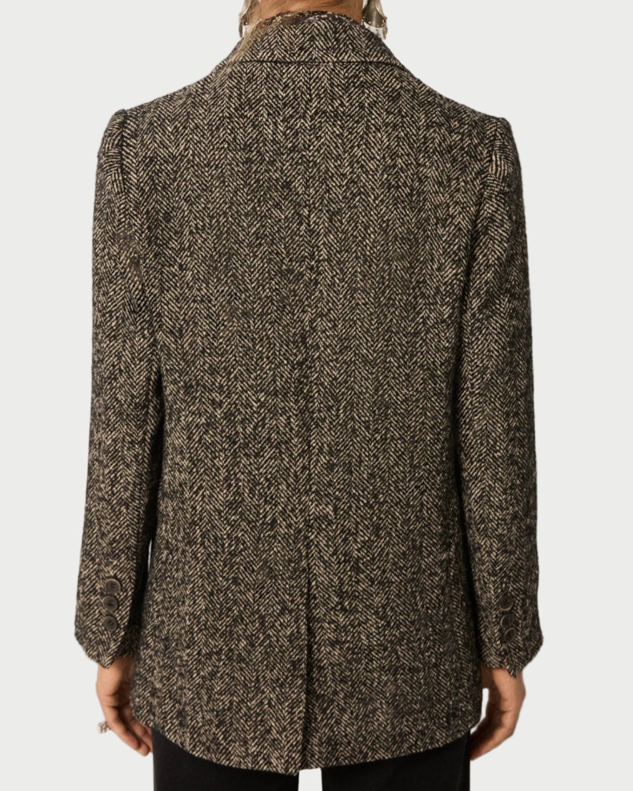 Back view of a person wearing a patterned coat on a plain background