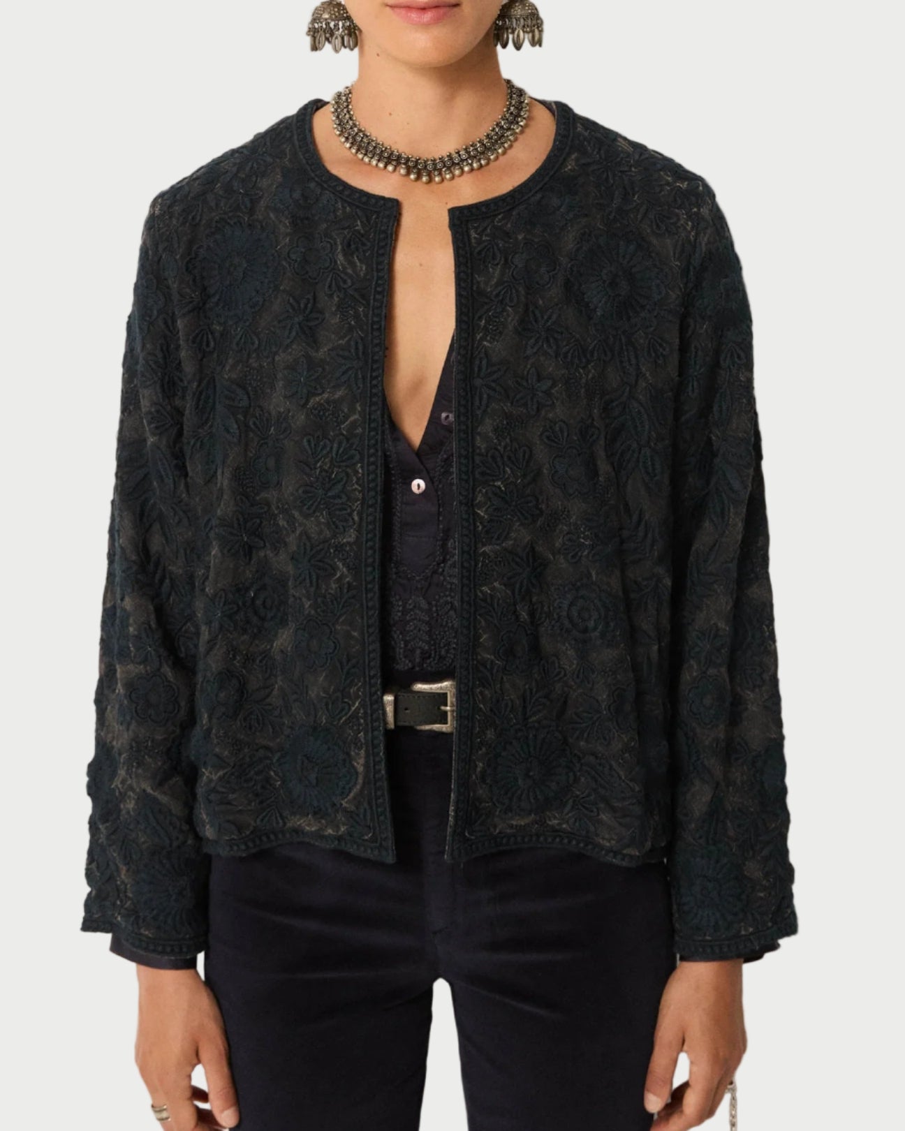 Person wearing a dark patterned jacket on a plain background