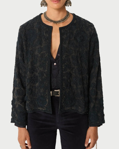 Person wearing a dark patterned jacket on a plain background