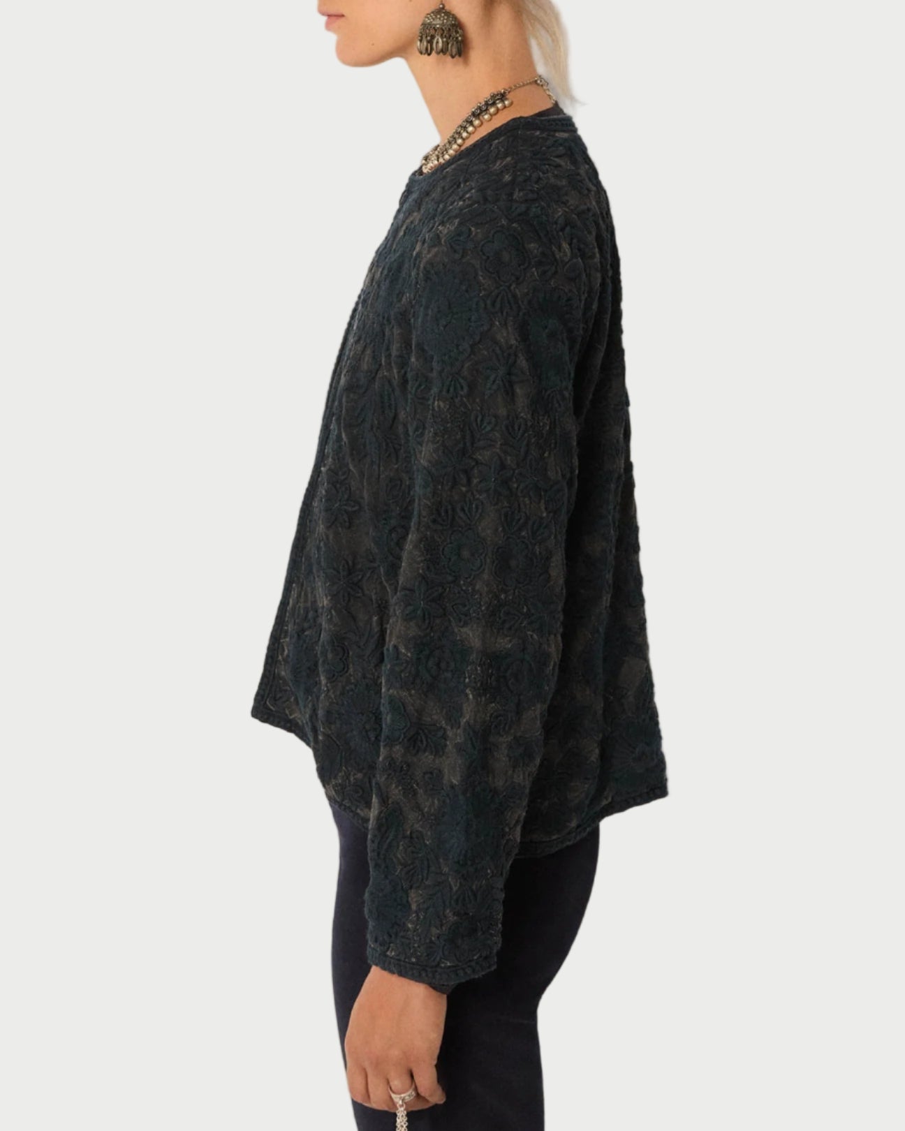 Person wearing a dark patterned sweater against a plain background