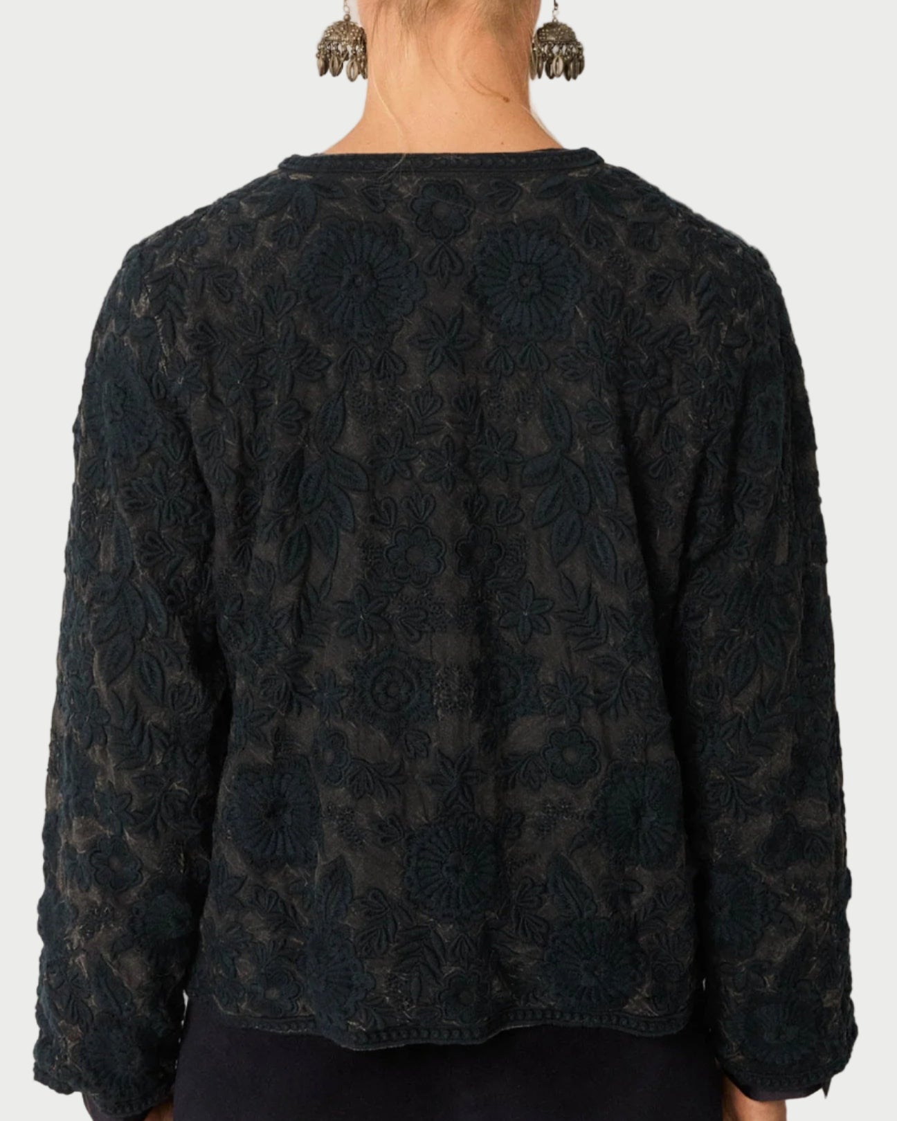 Person wearing a dark patterned top against a plain background