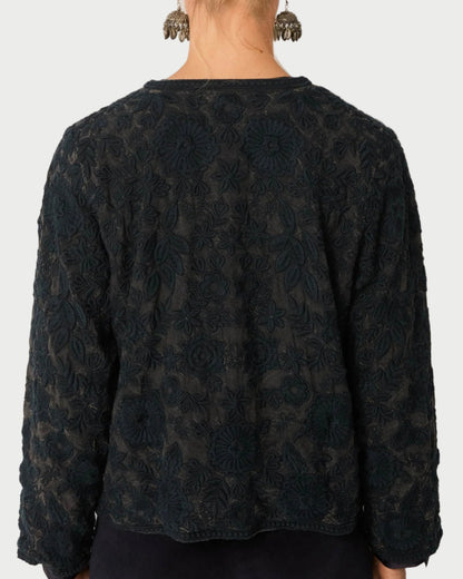 Person wearing a dark patterned top against a plain background