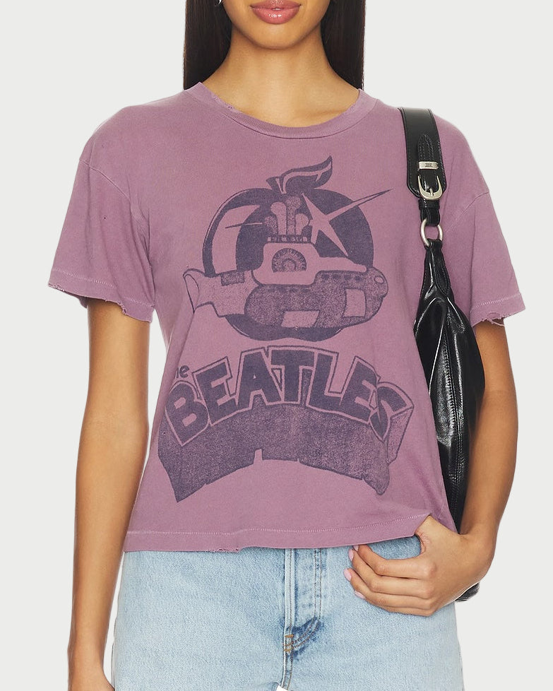 Woman wearing a purple 'The Beatles' t-shirt and denim shorts on a white background