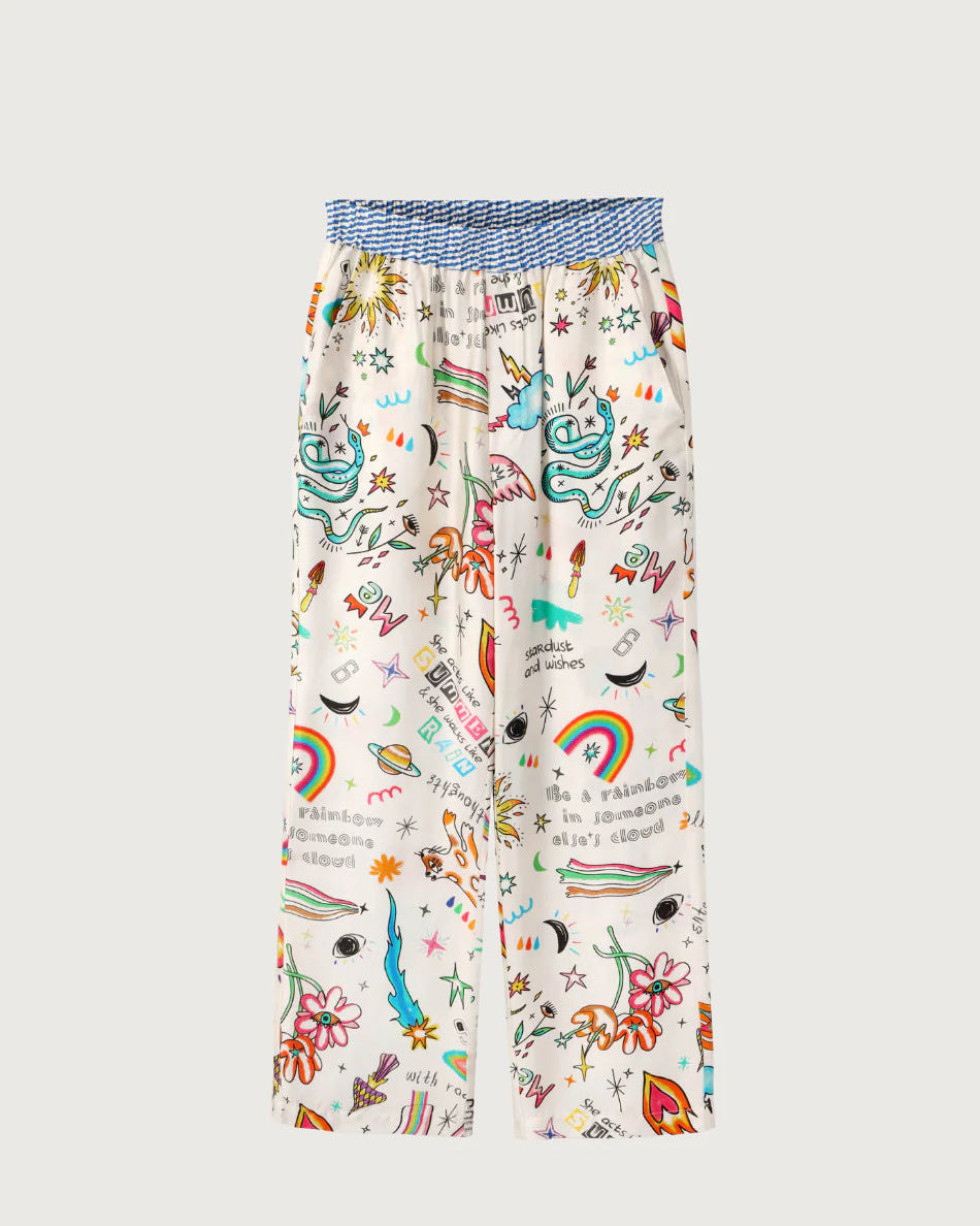 The ME369 Bailey Pants by ME369 feature a white base with colorful doodles—rainbows, snakes, eyes, stars, flowers, and planets—and a blue-and-white elastic waistband. These wide-leg pants are perfect for dopamine dressing.