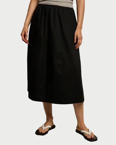 Person wearing a black skirt and beige top against a plain background