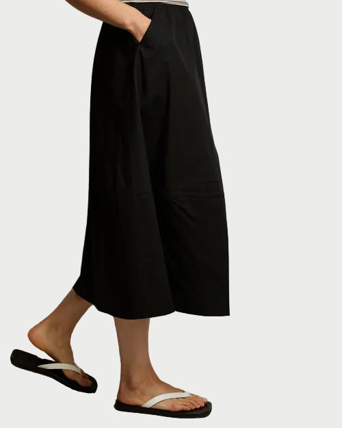 Person wearing black skirt and a striped top against a neutral background