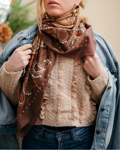 Woman wearing a patterned scarf and denim jacket outdoors