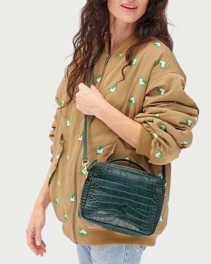 Woman holding a green handbag against a white background