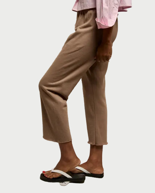 Person wearing a pink top and beige pants against a plain background