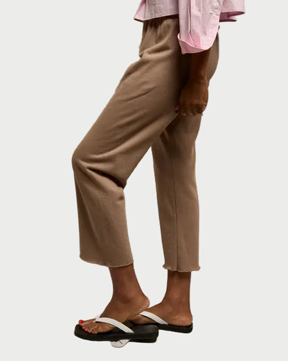 Person wearing a pink top and beige pants against a plain background