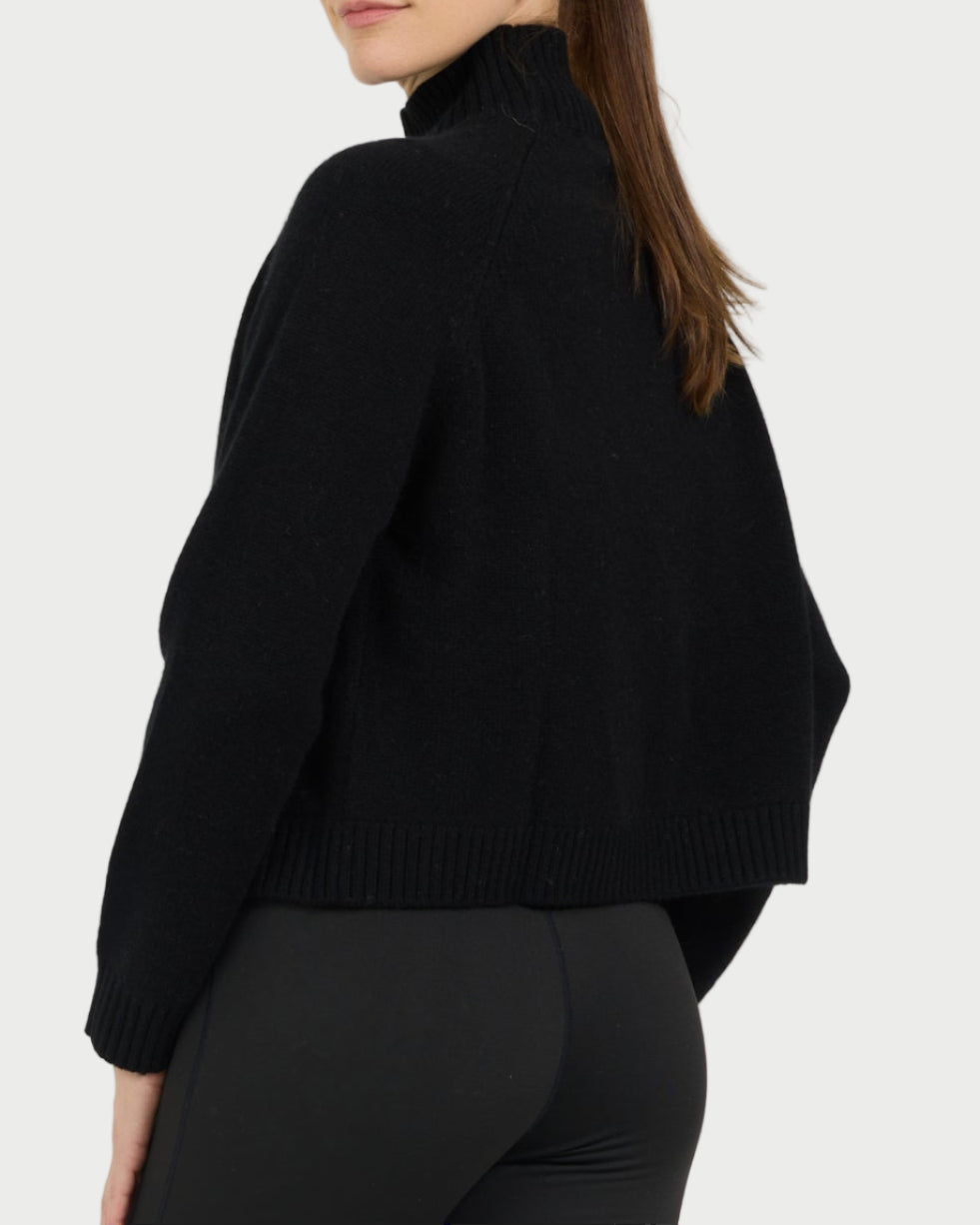 Person wearing a black outfit with beige shoes on a white background