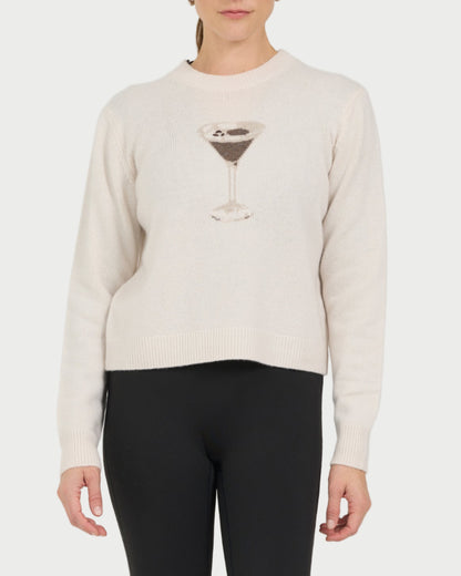 Person wearing a beige sweater with a martini glass design and black leggings on a white background