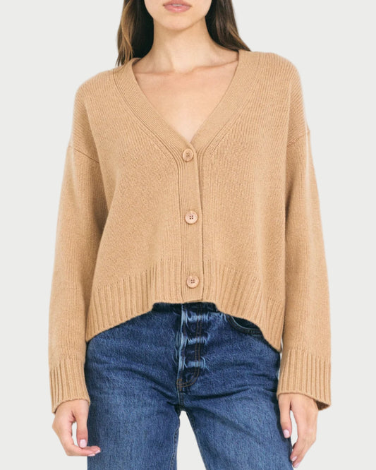Woman wearing a beige cardigan and blue jeans on a white background