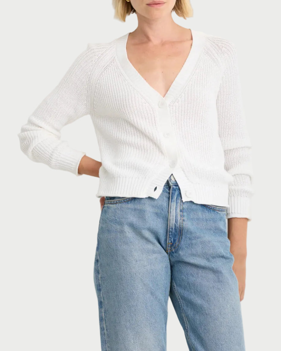 Woman wearing a white sweater and blue jeans against a white background