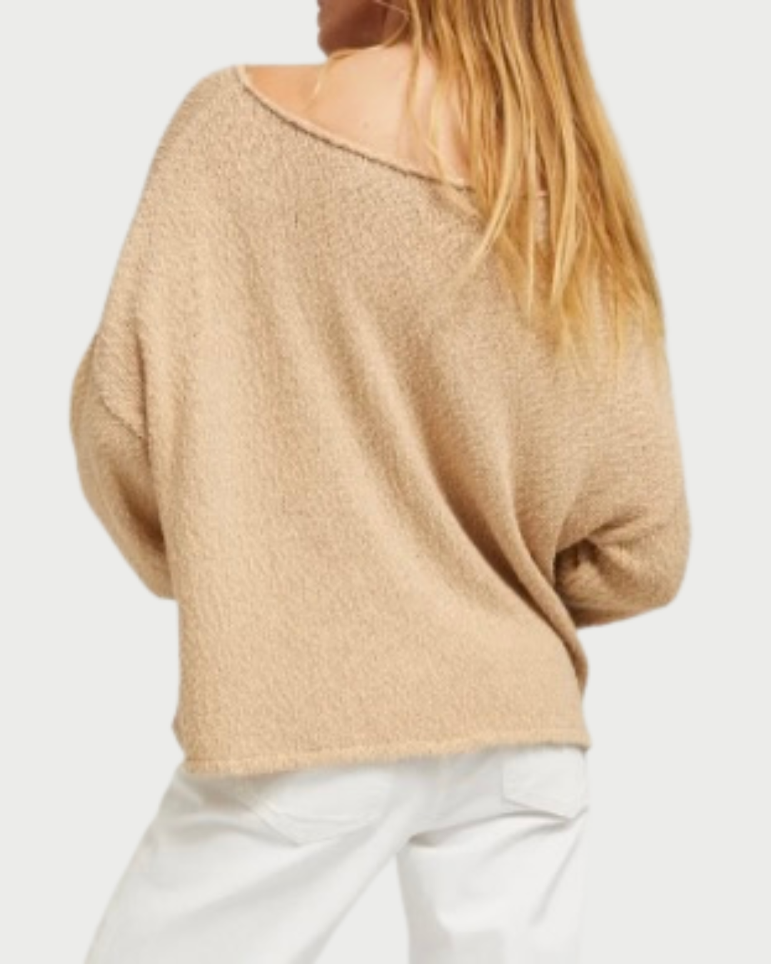 A person with long blonde hair, seen from the back against a white background, wears the SPRWMN Off Shoulder Sweater in beige by SPRWMN paired with white pants.