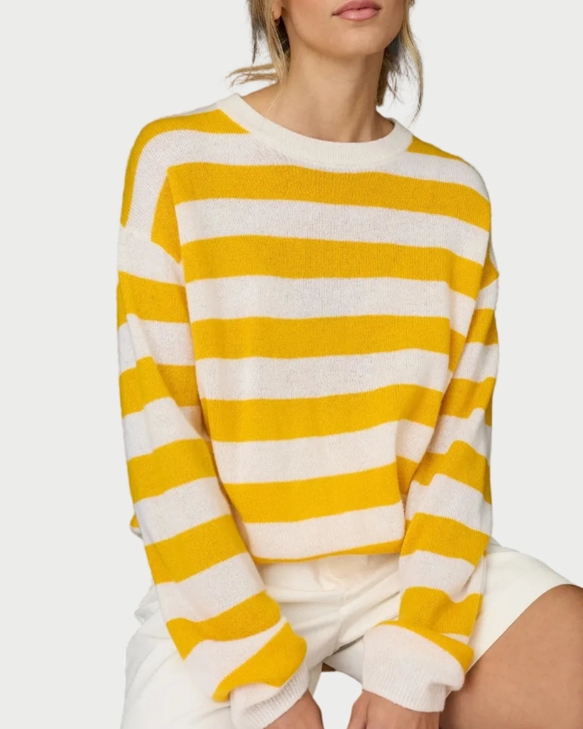Woman wearing a yellow and white striped sweater against a black background