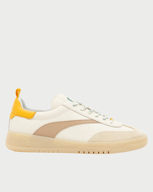 The Oncept Panama Sneaker is a stylish beige and cream low-top with a mustard-yellow heel accent, a beige side stripe, and a light tan sole. It features white laces on a plain light gray background.
