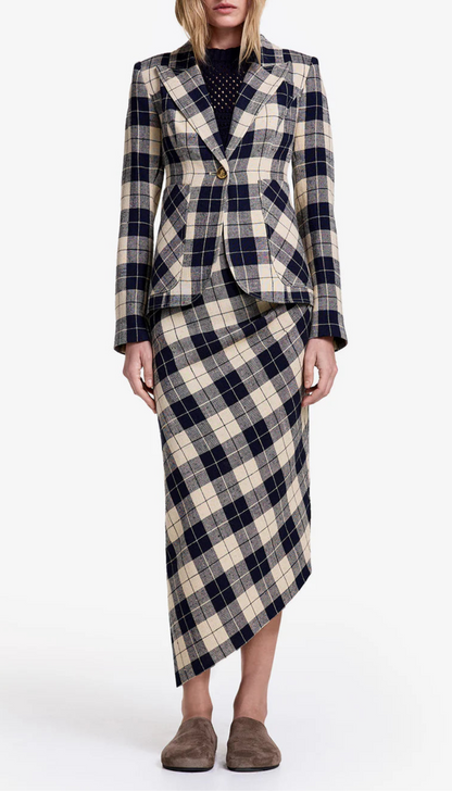 A person models the Smythe Asymmetrical Plaid Skirt with a matching beige and navy plaid blazer, dark top, and brown slip-on shoes against a white background.