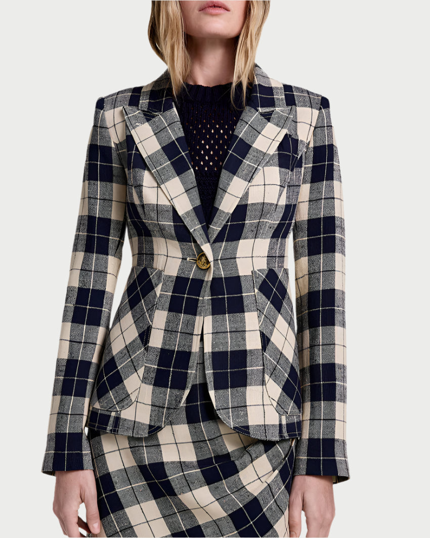 A woman wears the Smythe Patch Pocket Duchess Plaid Blazer in navy with a single button, teamed with a matching skirt and dark textured top, posing against a plain background.