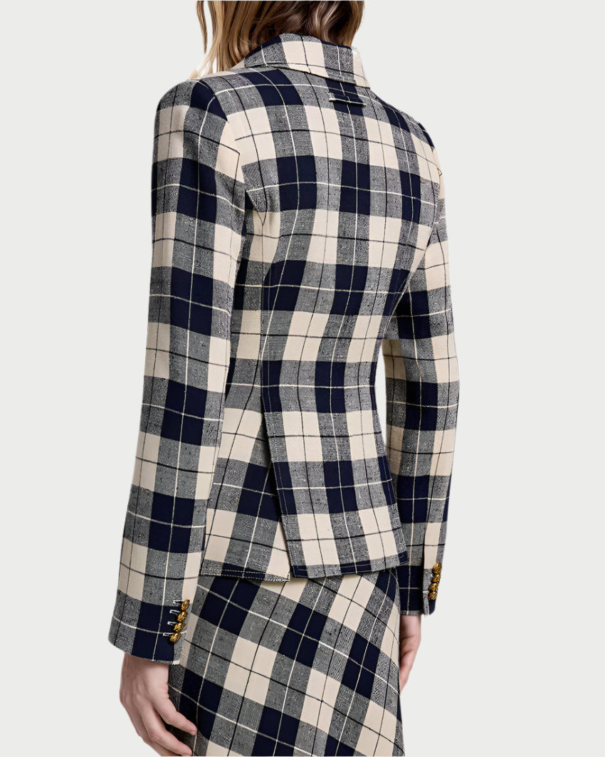 A person seen from the back wears the Smythe Patch Pocket Duchess Plaid Blazer with matching skirt, featuring navy plaid, gray, and cream checks and decorative buttons on the cuffs.