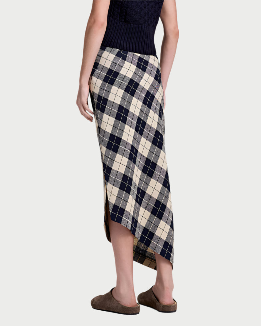 A person wearing the Smythe Asymmetrical Plaid Skirt, featuring a navy and beige pattern, pairs it with a dark sleeveless top and brown slippers while standing with their back to the camera.