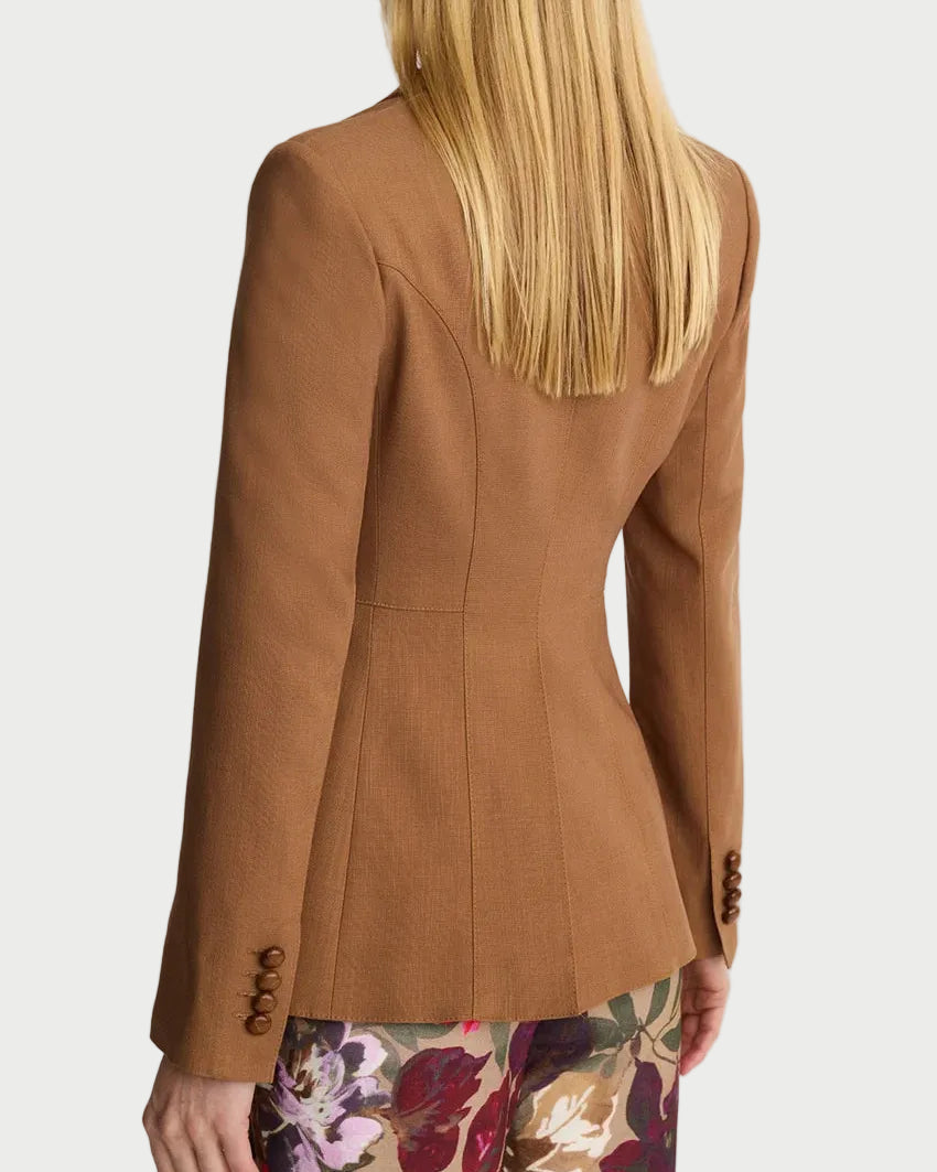 Person wearing a brown blazer with floral pants on a white background