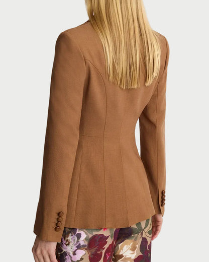 Person wearing a brown blazer with floral pants on a white background
