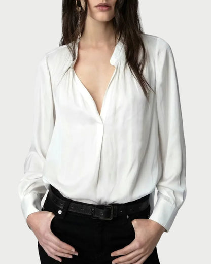 Woman wearing a white blouse with a deep neckline on a plain background