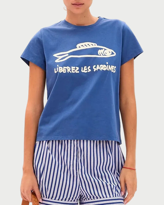 Woman wearing a blue t-shirt and striped shorts, holding a straw bag on a white background