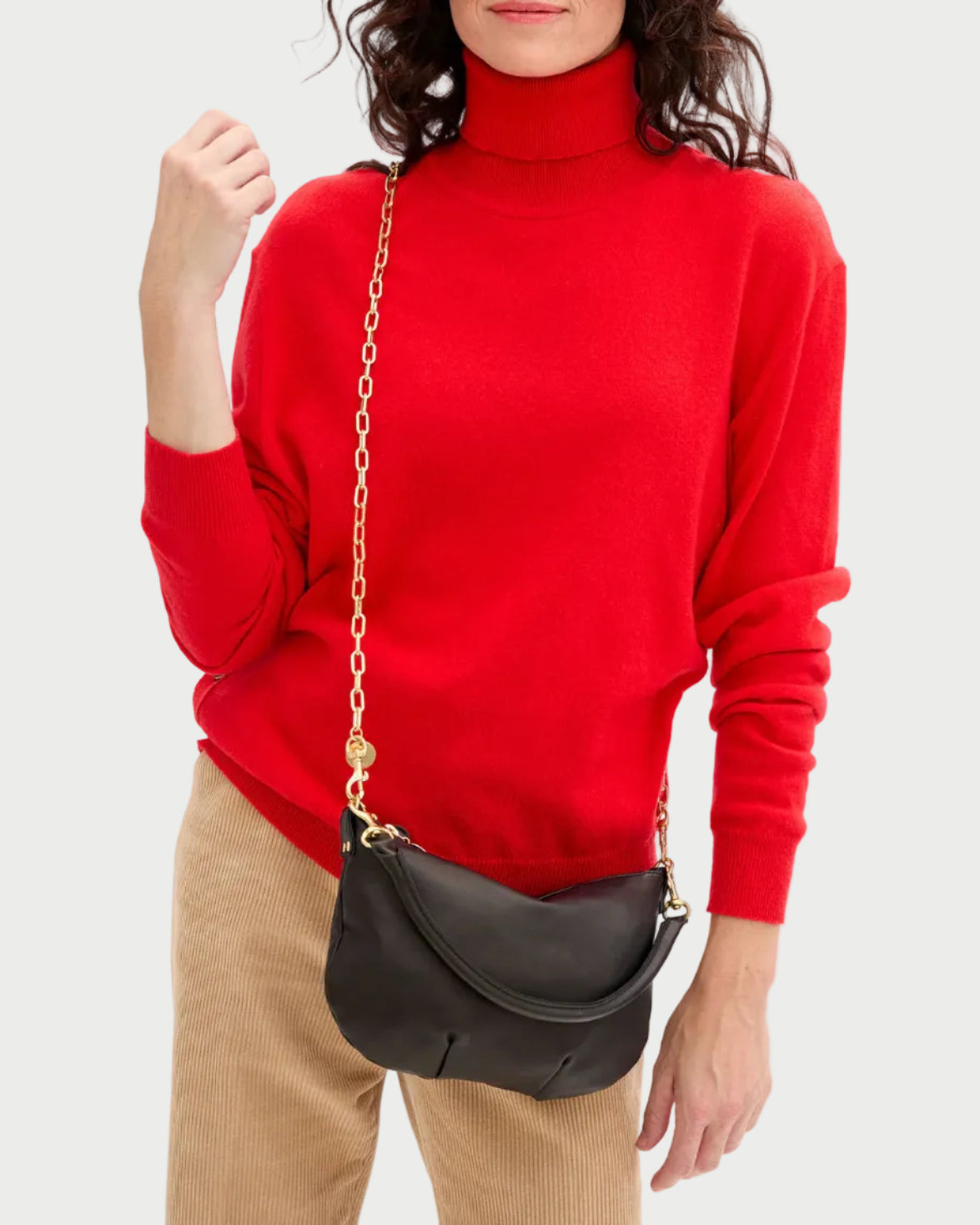 Person wearing a red sweater holding a black handbag with a gold chain.