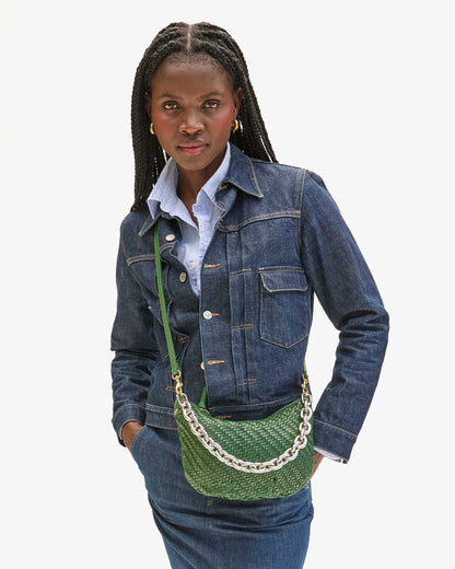 Woman wearing a denim jacket with a green handbag on a white background