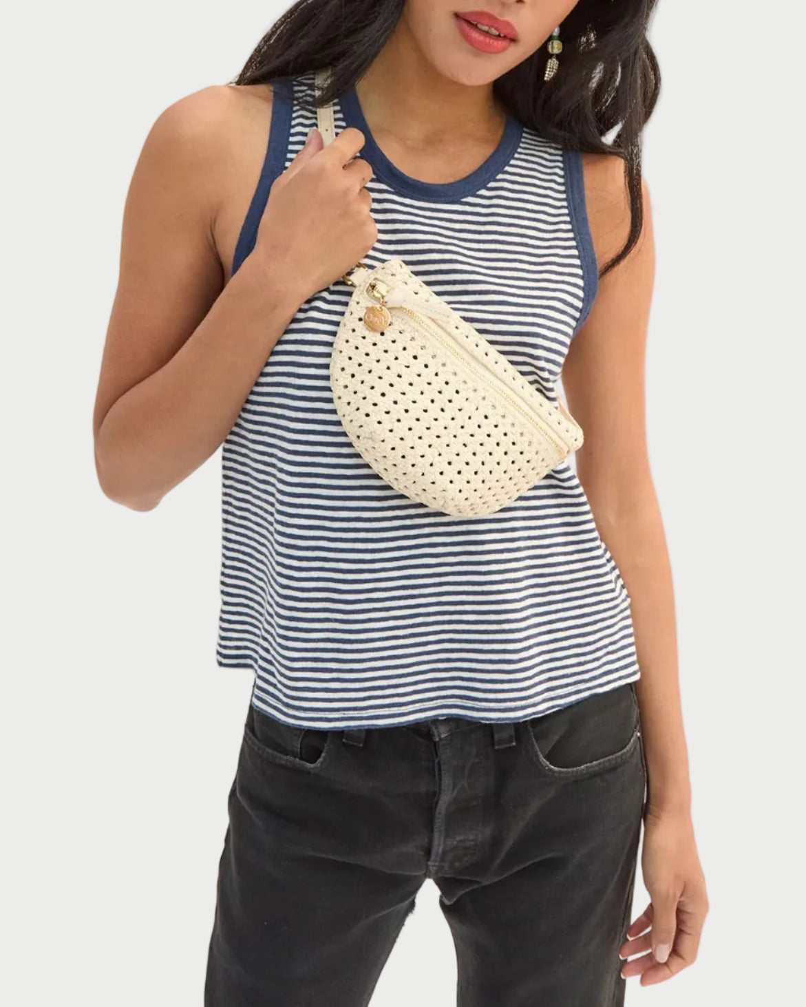 Woman holding a white woven handbag against a plain background